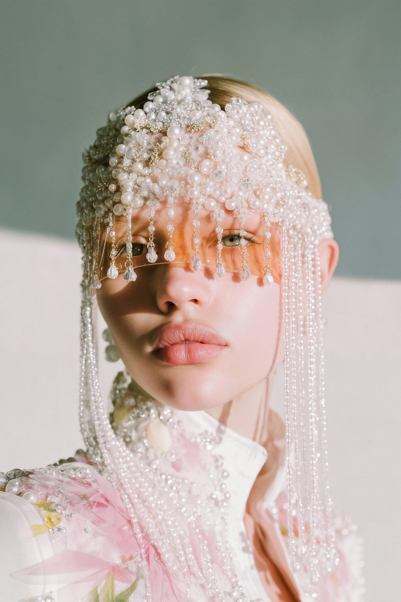 AI close-up of model wearing pearl-embroidered headdress with pink floral details, photoreal couture tone