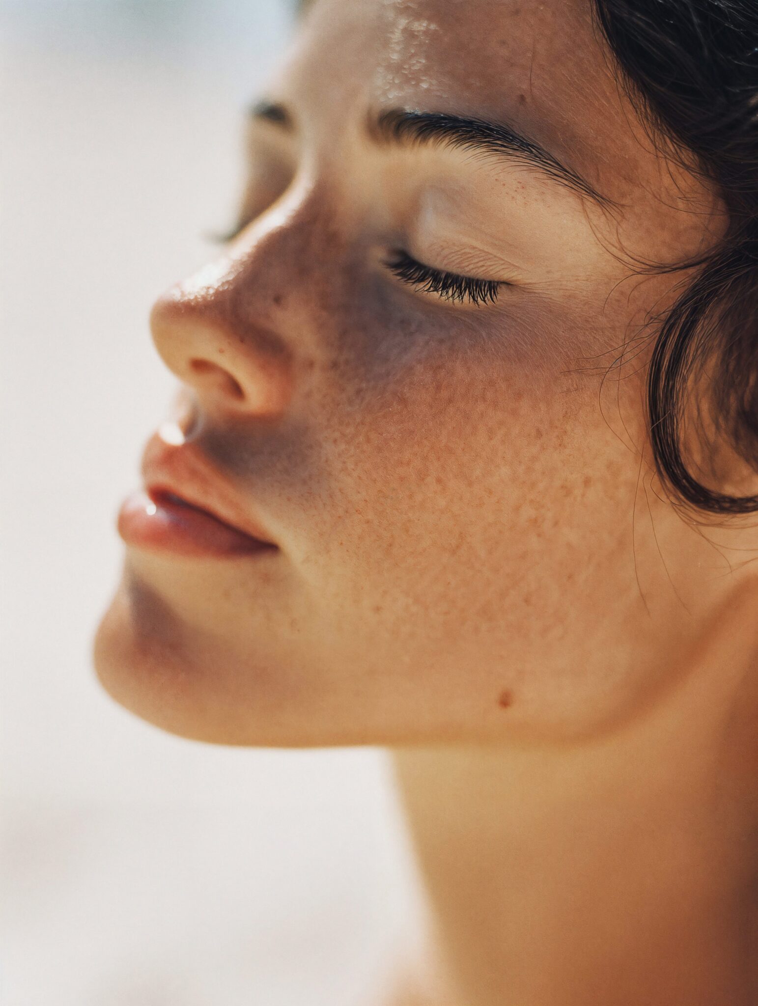 Photoreal AI beauty visual showing natural freckles and sunlight on skin, shade-true texture, cinematic macro still